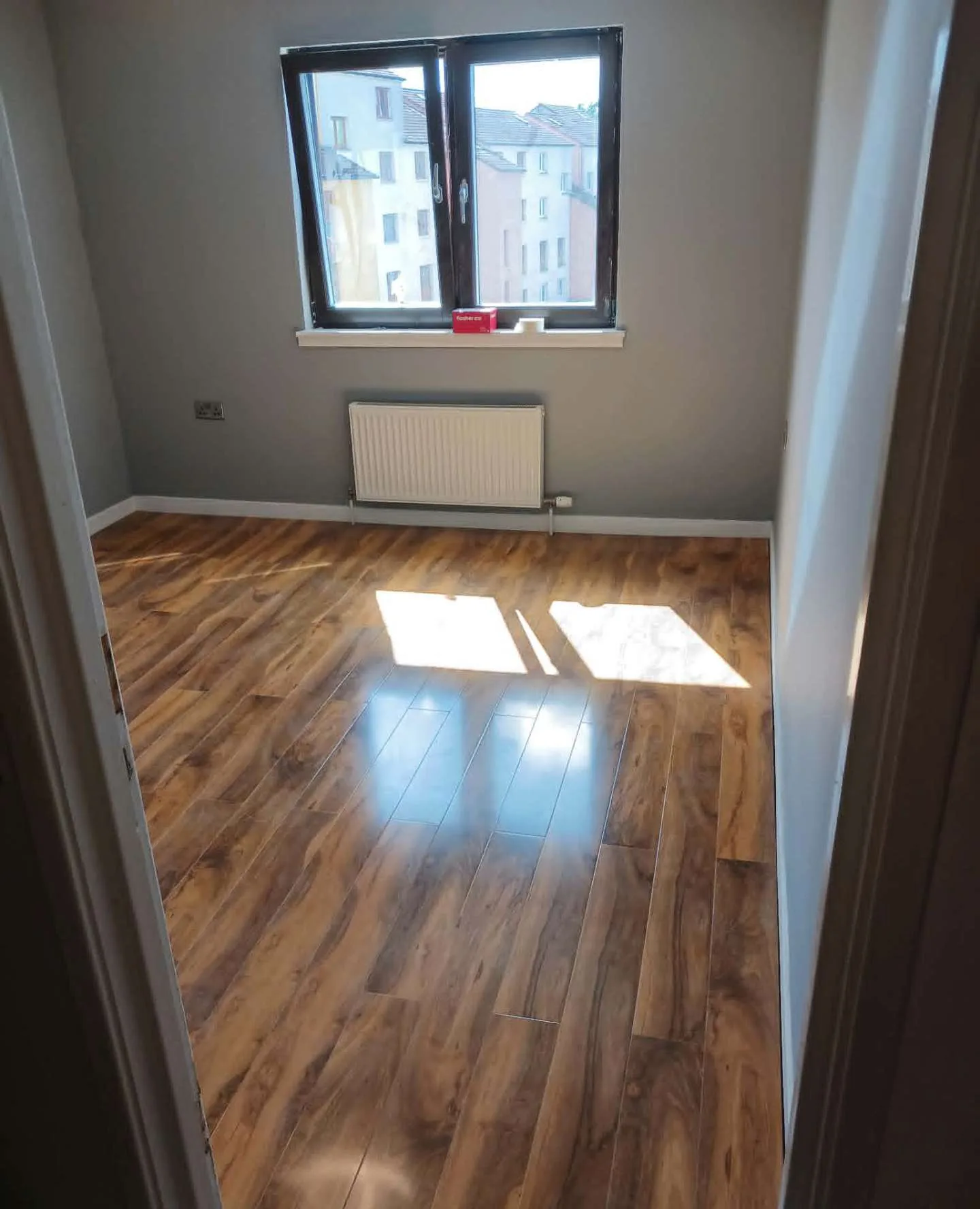 High-gloss oak laminate floor freshly laid in a bright bedroom