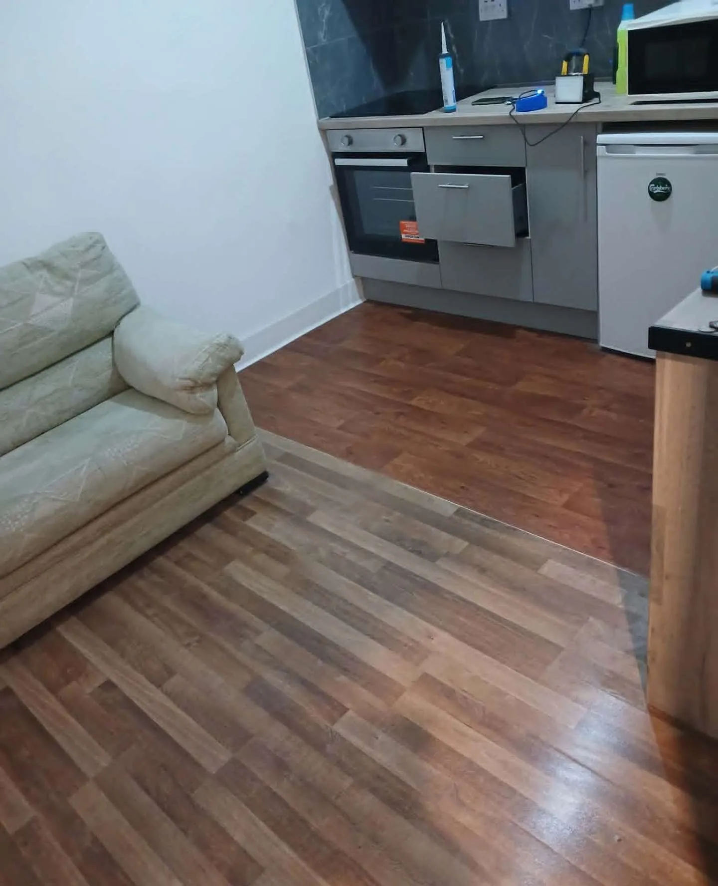 Wood-effect vinyl flooring laid through a studio living and kitchen area